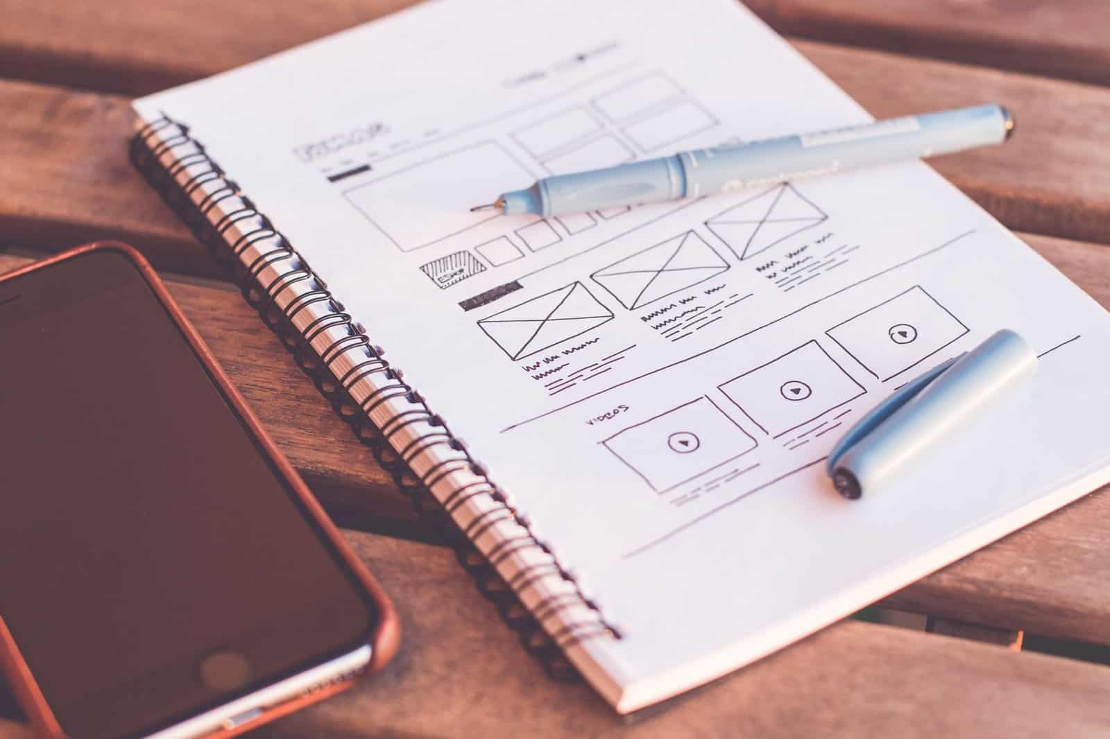 Escritorio con wireframes impresos y portátil durante la revisión de un proyecto web