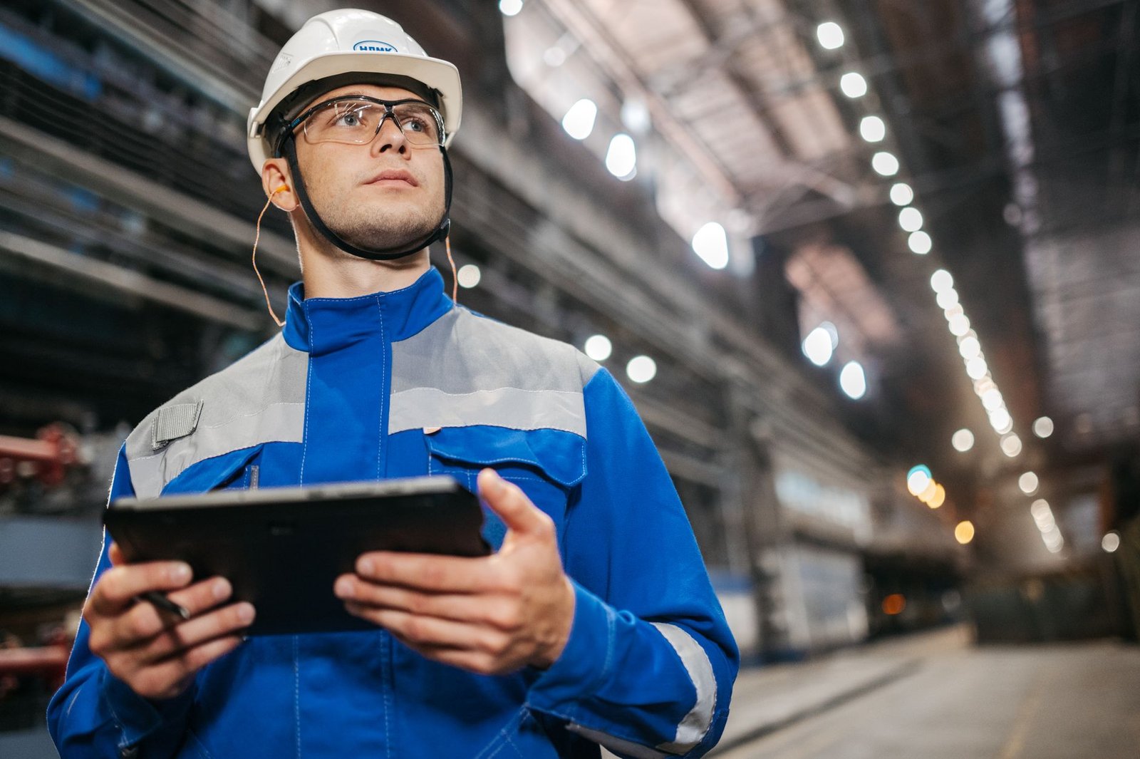 Ingeniero revisando datos junto a maquinaria en una nave de producción industrial